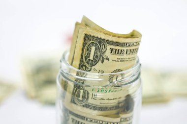Makro fotoğrafçılıkta cam kavanozlu ahşap bir masanın üzerinde Amerikan Doları banknotları. Para tasarruf kavramı.