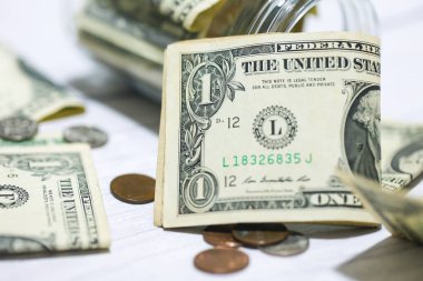 Makro fotoğrafçılıkta cam kavanozlu ahşap bir masanın üzerinde Amerikan Doları banknotları. Para tasarruf kavramı.