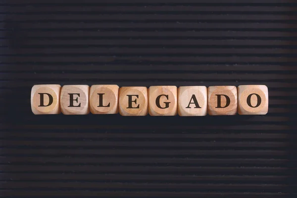 用巴西葡萄牙语在木制立方体上书写的题词Delegate 黑色背景 — 图库照片