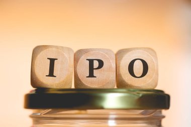 Tahta zarlar üzerine yazılmış halka arz kısaltması cam para tasarrufu kavanozunun üzerinde duruyor. Stüdyo fotoğrafı.