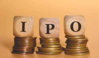 Tahta zarlar üzerine yazılmış halka arz kısaltması bozuk para yığınlarının üzerinde duruyor. Stüdyo fotoğrafı.