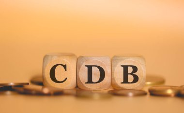 Brezilya Portekizcesi Banka Mevduat Sertifikası için tahtadan küplere ve bozuk para yığınlarına yazılmış CDB kısaltması. Stüdyo fotoğrafı.