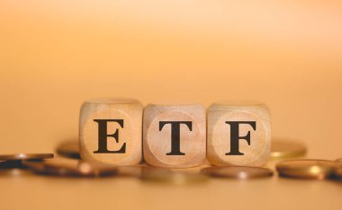 ETF Ticaret Fonu kısaltması. Tahta küplere ve bozuk para yığınlarına yazılmış. Stüdyo fotoğrafı.