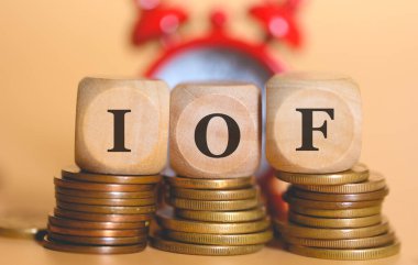 Tahta küplere ve bozuk para yığınlarına IOF 'un kısaltması. Stüdyo fotoğrafı.