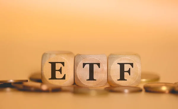 ETF Ticaret Fonu kısaltması. Tahta küplere ve bozuk para yığınlarına yazılmış. Stüdyo fotoğrafı.