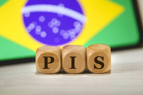 木製のキューブに書かれたブラジルポルトガル語で社会統合プログラムのためのPisの頭字語 構成で画面上のブラジルの旗を持つ携帯電話 — ストック写真