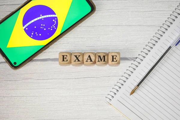 木製のテーブルの上に木製の立方体に書かれたポルトガル語でのテキストExam 組成物中のブラジルの旗を持つノートブック 携帯電話 — ストック写真