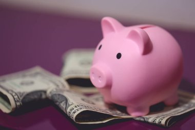 Mor bir ahşap mobilya üzerinde bir kumbara ve Amerikan doları banknotları. Finans kavramı.