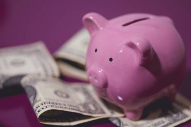 Mor bir ahşap mobilya üzerinde bir kumbara ve Amerikan doları banknotları. Finans kavramı.
