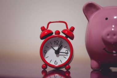 Kumbaranın ve çalar saatin yakın görüntüsü. Finans ve zaman kavramları.