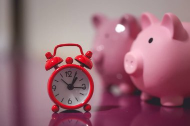 İki kumbara ve çalar saatin yakın çekim görüntüsü. Finans ve zaman kavramları.