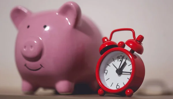 Close-up view of piggy bank and an alarm clock. Finance and time concepts.