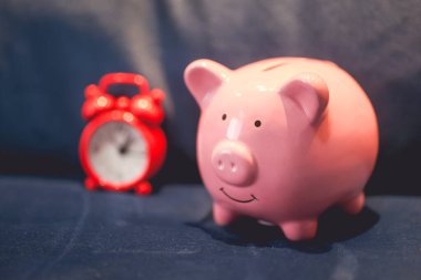 Kumbaranın ve çalar saatin yakın görüntüsü. Finans ve zaman kavramları.