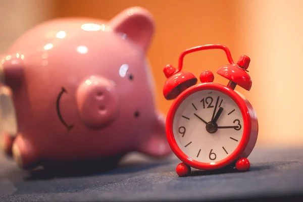 Close-up view of piggy bank and an alarm clock. Finance and time concepts.