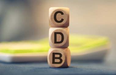 Brezilya Portekizcesi Banka Mevduat Sertifikası 'nın kısaltması. Tahta küplere yazılmış. Kompozisyonda bir hesap makinesi. 