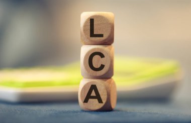 Tahta küplere yazılmış LCA kısaltması. Kompozisyonda bir hesap makinesi. 