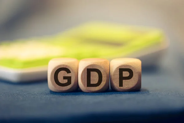 stock image The acronym GDP for Gross domestic product written on wooden cubes. A calculator in the composition. 