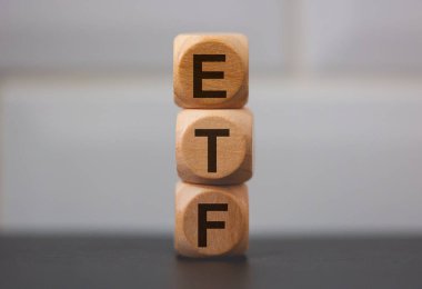 ETF acronym for Exchange Traded Fund written on wooden cubes on grey background clipart