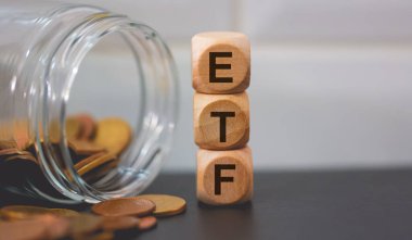 ETF Ticaret Fonu kısaltması. Tahta küplere ve bozuk para yığınlarına yazılmış. Stüdyo fotoğrafı.