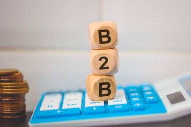 Tahta küplere yazılmış B2B kısaltması. Kompozisyonda bir hesap makinesi. 