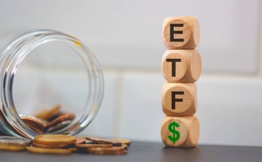 ETF Ticaret Fonu kısaltması. Tahta küplere ve bozuk para yığınlarına yazılmış. Stüdyo fotoğrafı.