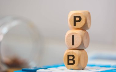 PIB kısaltması tahta küplere yazılmış. Kompozisyonda bir hesap makinesi. 