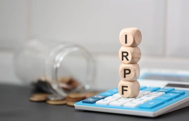 The acronym IRPF written on wooden cubes. A calculator in the composition.  clipart