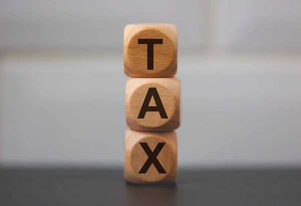 用灰色背景的木制立方体写的字Tax — 图库照片