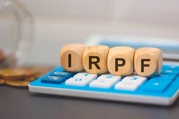 stock image The acronym IRPF written on wooden cubes. A calculator in the composition. 