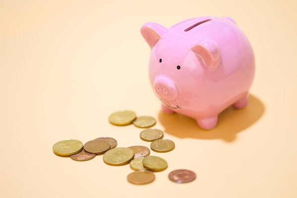 Close-up view of pink piggy bank and coins. Finance concept.