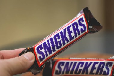 Snickers çikolatası tutan kişinin yakın plan görüntüsü
