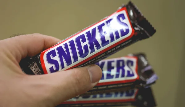持Snickers巧克力棒的人的特写镜头 — 图库照片