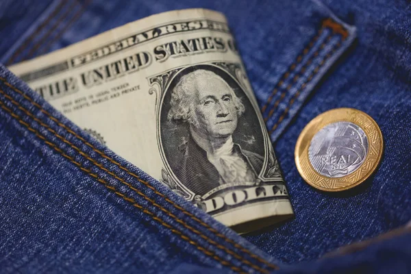 Real coin and United States dollar bills in a jeans pocket in macro photo.