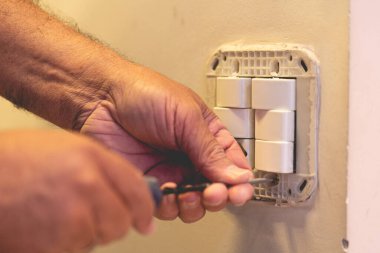 Adam duvara bir elektrik düğmesi bağlıyor.