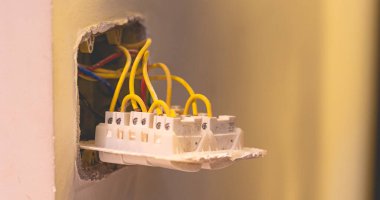 Adam duvara bir elektrik düğmesi bağlıyor.