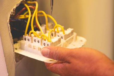 Adam duvara bir elektrik düğmesi bağlıyor.