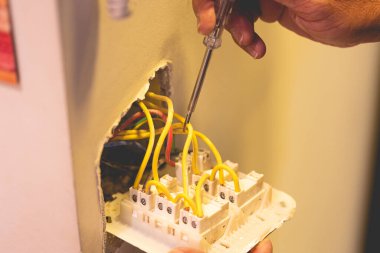 Adam duvara bir elektrik düğmesi bağlıyor.