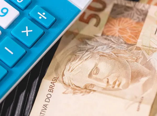 Brazilian Real notes on a calculator. Brazilian economy, finance and income tax.
