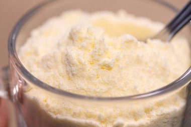 Bir kaşık dolusu süt tozu. Arkaplanda kutu. 