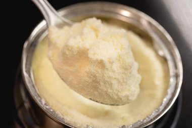 Bir kaşık dolusu süt tozu. Arkaplanda kutu. 