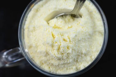 Bir kaşık dolusu süt tozu. Arkaplanda kutu. 