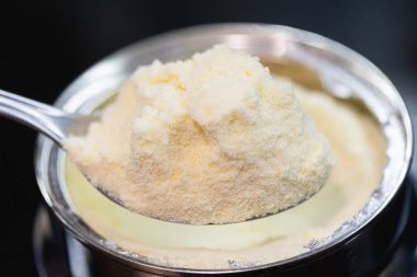 Bir kaşık dolusu süt tozu. Arkaplanda kutu. 