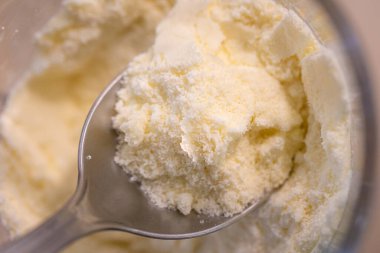 Bir kaşık dolusu süt tozu. Arkaplanda kutu. 