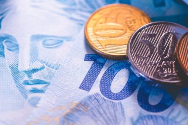 Brezilya Real 100 reais banknotu ve Brezilya sikkelerine yakın çekim. Brezilya ekonomisi, finans, vergi ve enflasyon