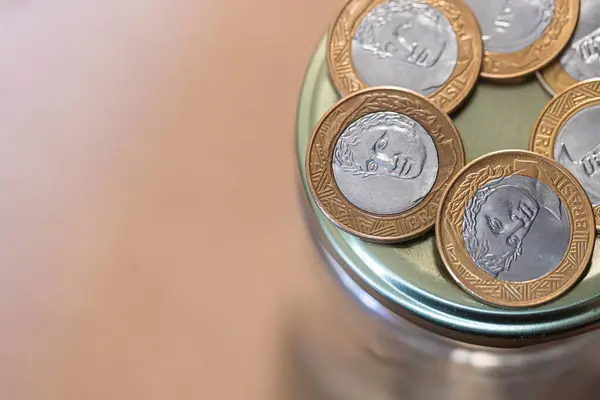 stock image Pile of one real coins on a glass jar piggy bank. Finance, investments, inflation and the Brazilian economy. Brazilian Real, BRL. 