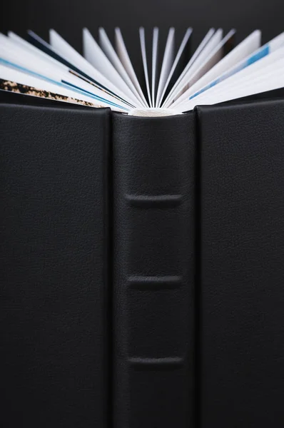 A beautiful leather bound book against a black background. Stylish book WITH OPEN PAGES on dark black background. The texture of a photobook made of genuine leather.