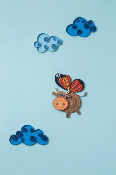 Stock image Happy cute cow flying in the sky between clouds. A little cow with butterfly wings. Happiness, dreaming and freedom concept. Hand made of paper quilling technique.