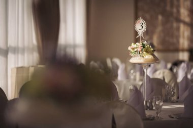 Düğün için. Ziyafet. Sandalyeler ve yuvarlak masa misafirler için çatal bıçak, çiçek ve çanak çömlek ile servis ediliyor ve masa örtüsüyle kaplanıyor. Pastel tonlarında klasik bir düğün için şık bir düğün dekoru..