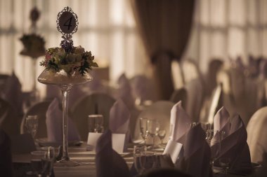 Düğün için. Ziyafet. Sandalyeler ve yuvarlak masa misafirler için çatal bıçak, çiçek ve çanak çömlek ile servis ediliyor ve masa örtüsüyle kaplanıyor. Pastel tonlarında klasik bir düğün için şık bir düğün dekoru..