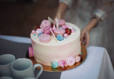 Pembe doğum günü pastası. Doğum günü pastası tezgahta. Elinde renkli süslemeli pasta var. Şenlik ikramı. Doğum günü pastası tutan kadın. Güzel bir doğum günü pastası ve bir partide badem kurabiyesi.